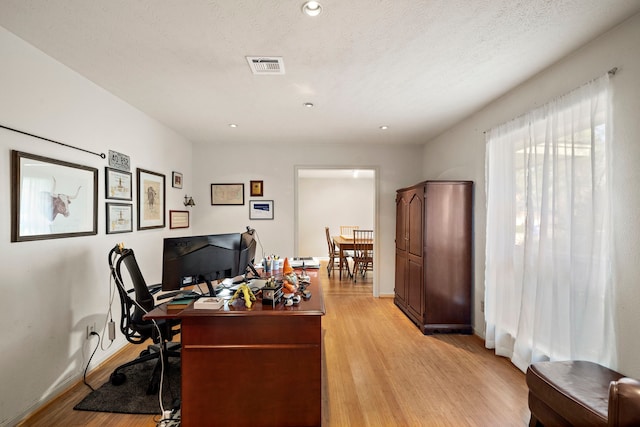 office space featuring visible vents, baseboards, recessed lighting, light wood-style floors, and a textured ceiling