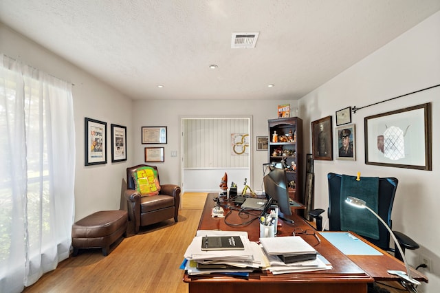 office featuring wood finished floors, visible vents, and a textured ceiling