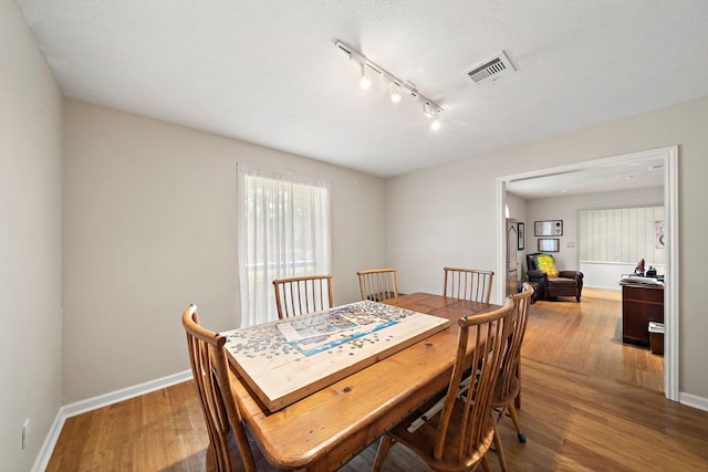 dining space with visible vents, baseboards, and wood finished floors