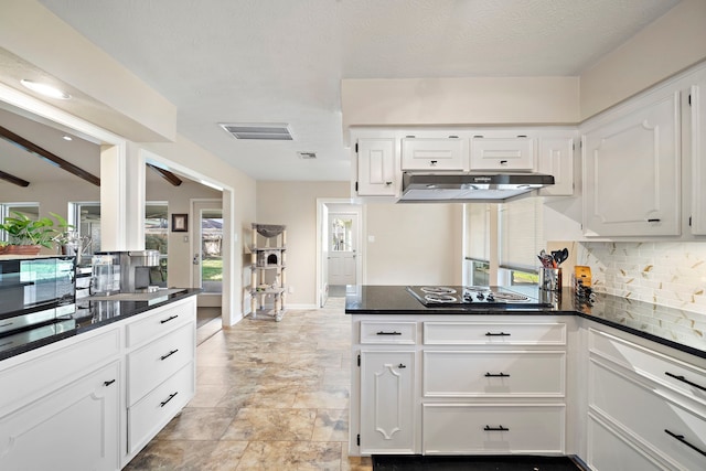 kitchen featuring under cabinet range hood, backsplash, dark countertops, and white cabinetry