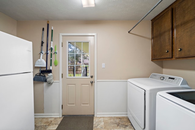 laundry area with cabinet space, a textured ceiling, independent washer and dryer, and wainscoting