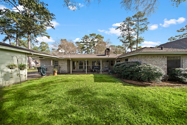 back of house with brick siding, a patio, and a yard