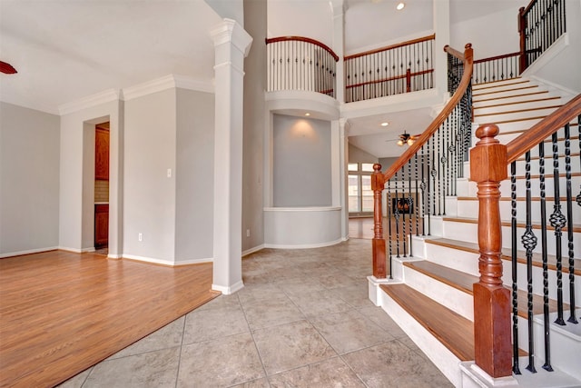 foyer featuring baseboards, ornate columns, ornamental molding, ceiling fan, and tile patterned floors