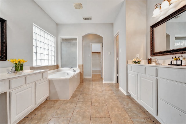 bathroom with two vanities, a bath, visible vents, and a stall shower