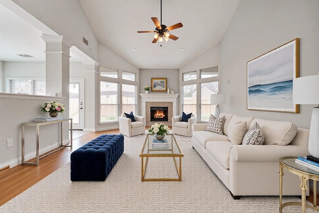 living room featuring visible vents, wood finished floors, a fireplace, baseboards, and ceiling fan