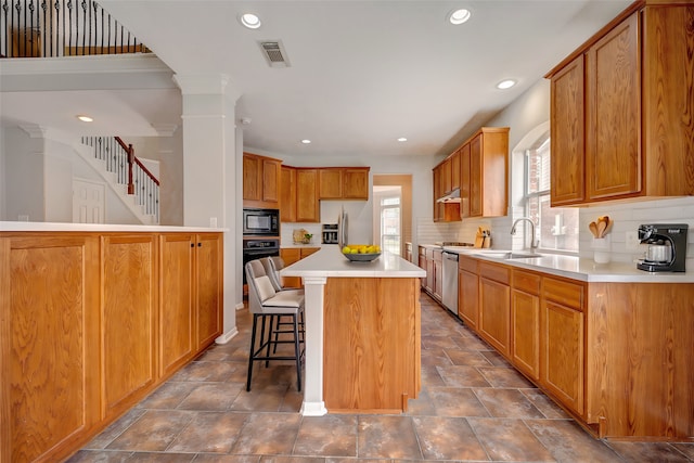 kitchen with backsplash, oven, black microwave, a breakfast bar, and light countertops