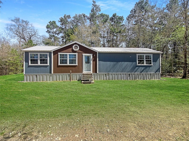 manufactured / mobile home with metal roof, a front yard, and entry steps