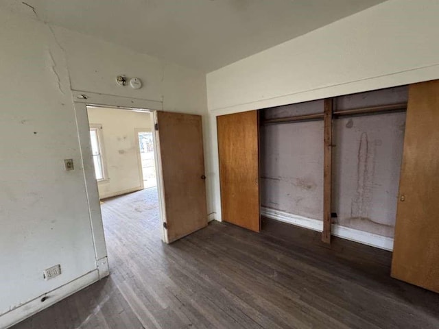 unfurnished bedroom with dark wood-style floors and a closet