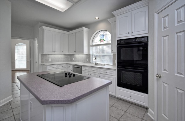 kitchen featuring black appliances, a sink, tasteful backsplash, light tile patterned flooring, and white cabinets