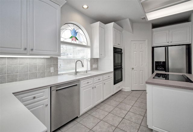 kitchen with black appliances, a sink, white cabinetry, light tile patterned flooring, and decorative backsplash