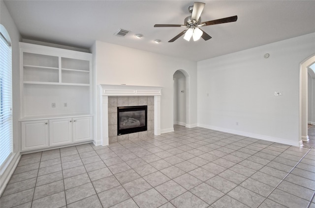 unfurnished living room with visible vents, baseboards, a fireplace, arched walkways, and ceiling fan