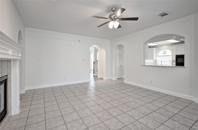 unfurnished living room featuring visible vents, a tile fireplace, baseboards, and ceiling fan