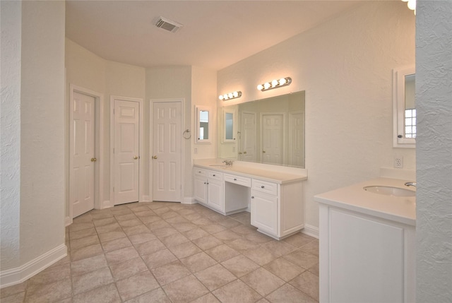 full bathroom with a sink, visible vents, two vanities, and a textured wall