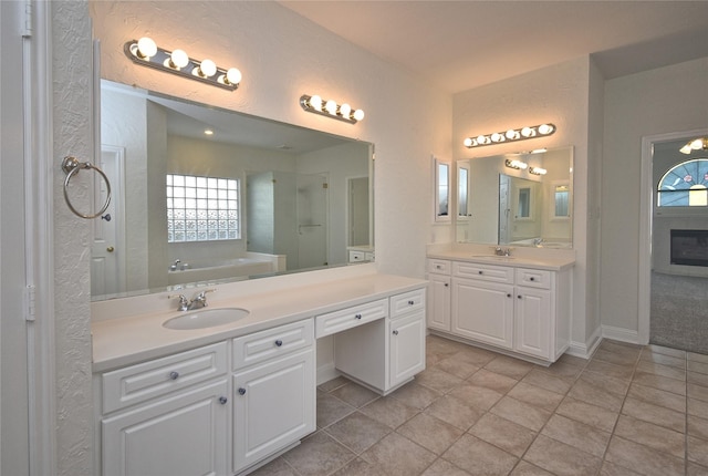 bathroom with a bath, two vanities, a wealth of natural light, and a sink