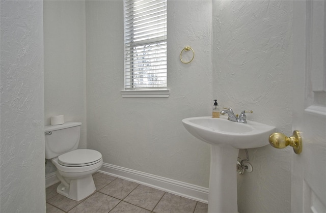 bathroom with tile patterned floors, baseboards, toilet, and a textured wall