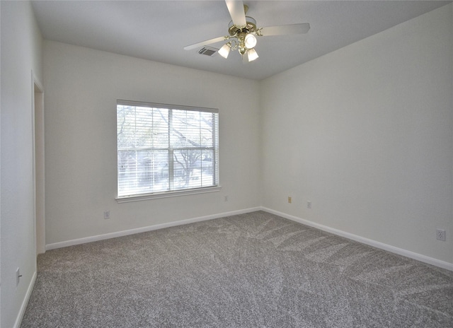 carpeted spare room with visible vents, baseboards, and ceiling fan