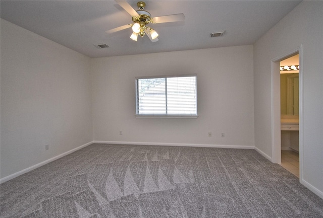 carpeted spare room featuring visible vents, baseboards, and ceiling fan