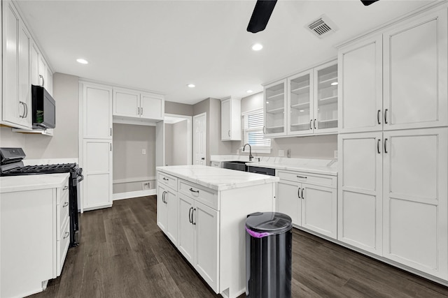 kitchen featuring visible vents, a sink, white cabinetry, black microwave, and gas range