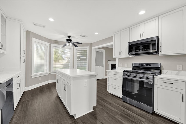 kitchen featuring dark wood finished floors, white cabinets, stainless steel appliances, and a ceiling fan