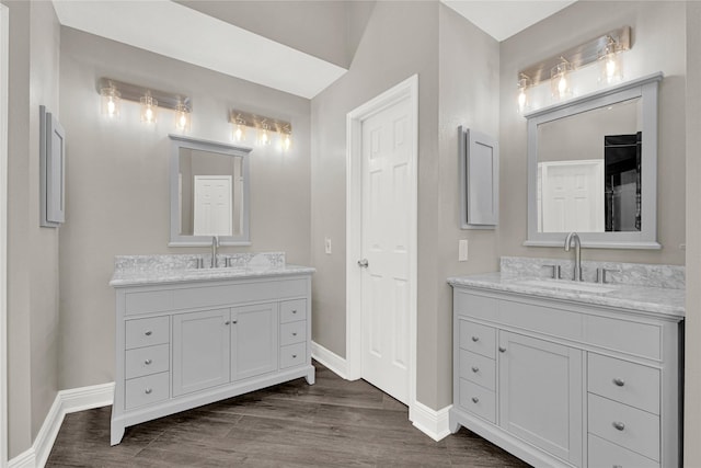 bathroom featuring wood finished floors, two vanities, and a sink