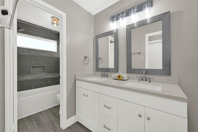 bathroom featuring a sink, toilet, wood finished floors, and double vanity