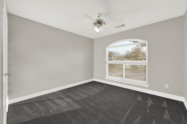 spare room with visible vents, a ceiling fan, baseboards, and dark carpet