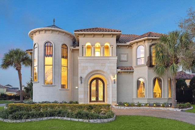 mediterranean / spanish-style house with a tiled roof, french doors, and stucco siding