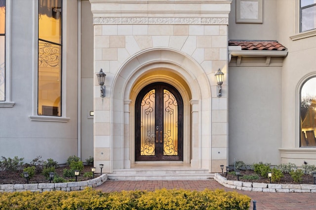 property entrance featuring a tiled roof, stone siding, and stucco siding