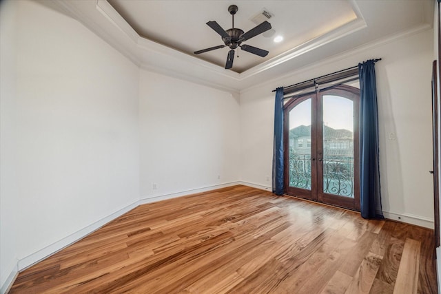 unfurnished room with visible vents, light wood-style flooring, french doors, crown molding, and a raised ceiling