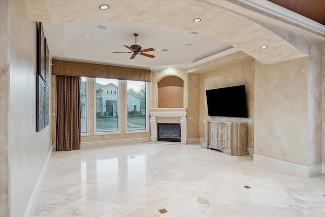 unfurnished living room with a glass covered fireplace, baseboards, a raised ceiling, and ceiling fan