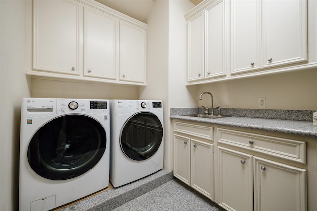 laundry area featuring washing machine and dryer, cabinet space, and a sink