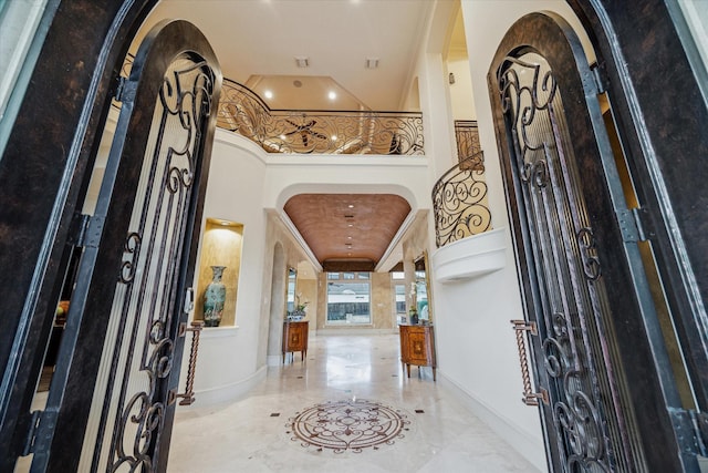 foyer entrance with baseboards, arched walkways, a high ceiling, and marble finish floor