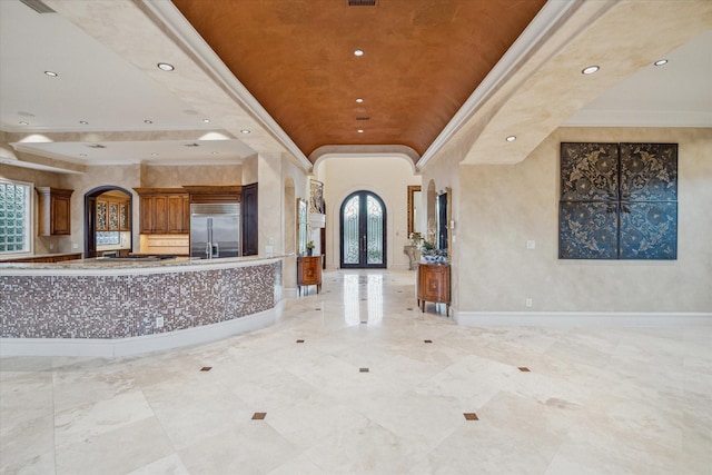 entrance foyer with arched walkways, plenty of natural light, crown molding, and a tray ceiling