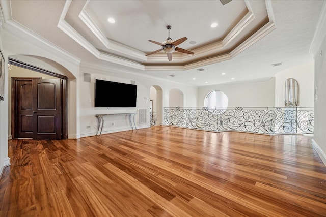 unfurnished living room featuring visible vents, ceiling fan, wood finished floors, arched walkways, and a raised ceiling