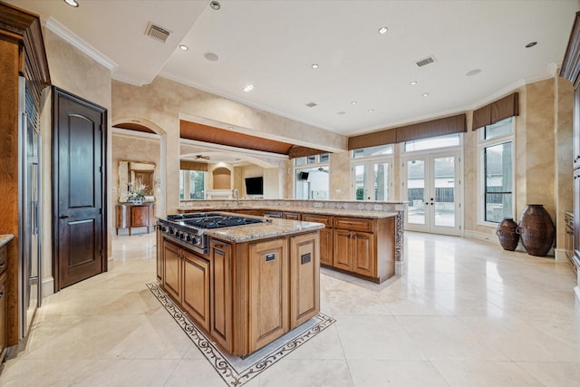 kitchen featuring visible vents, brown cabinets, ornamental molding, french doors, and stainless steel gas stovetop