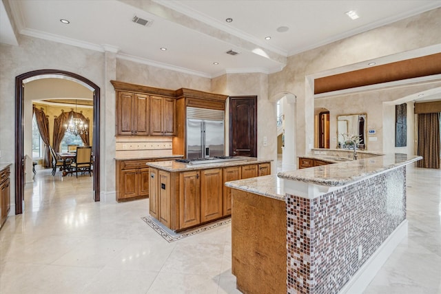 kitchen featuring light stone counters, visible vents, arched walkways, stainless steel built in fridge, and cooktop