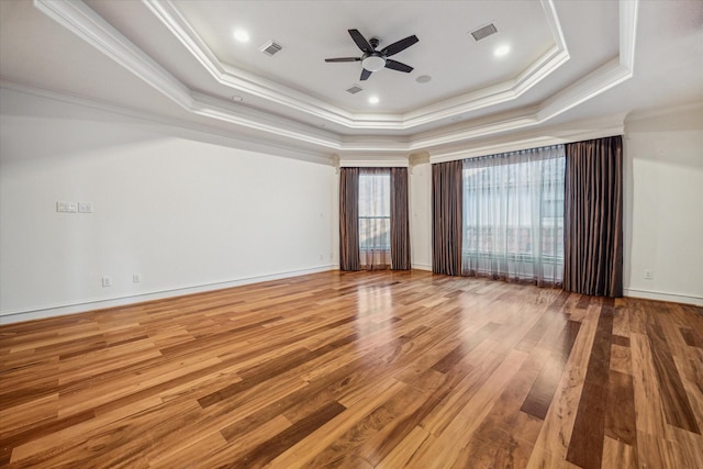 spare room featuring visible vents, ornamental molding, a tray ceiling, wood finished floors, and ceiling fan