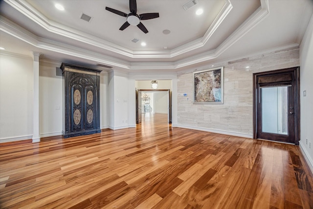 unfurnished living room featuring wood finished floors, visible vents, a raised ceiling, and ceiling fan