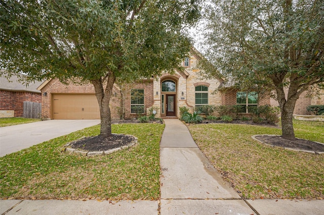 view of property hidden behind natural elements with a garage, brick siding, concrete driveway, and a front lawn