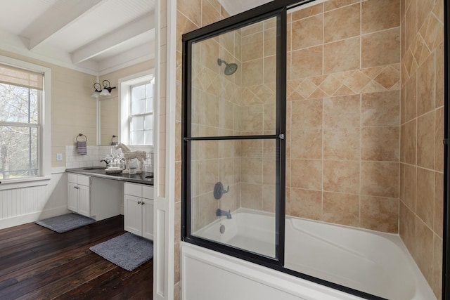 bathroom featuring vanity, wood finished floors, enclosed tub / shower combo, beam ceiling, and decorative backsplash