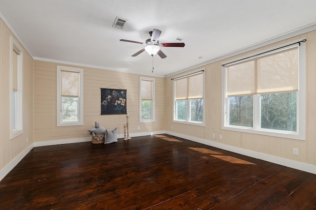 unfurnished living room with a ceiling fan, visible vents, baseboards, ornamental molding, and wood-type flooring