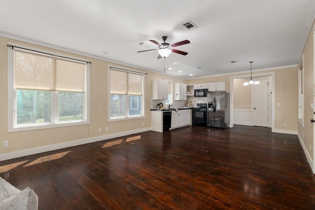 unfurnished living room featuring visible vents, ornamental molding, ceiling fan with notable chandelier, dark wood-style floors, and baseboards