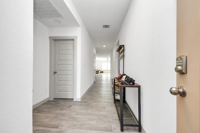 corridor featuring light wood-type flooring, visible vents, and baseboards