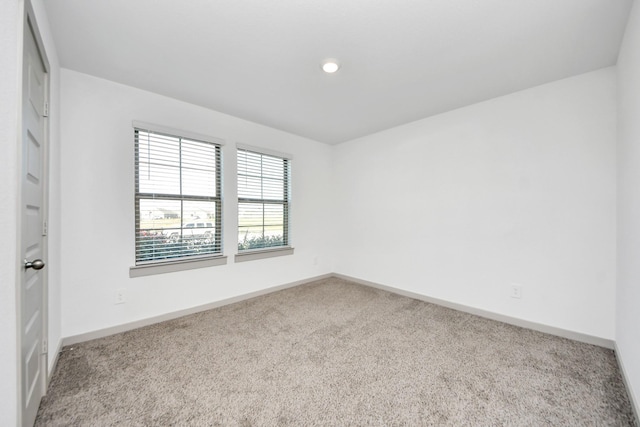 carpeted spare room featuring baseboards