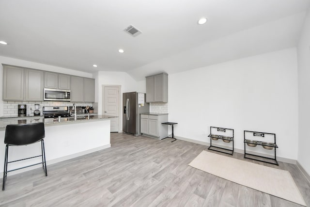 kitchen featuring stainless steel appliances, gray cabinetry, light wood-style flooring, and visible vents