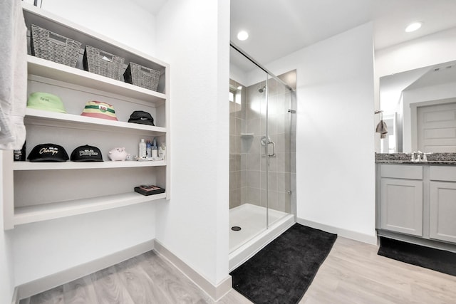 bathroom with baseboards, wood finished floors, a stall shower, and vanity