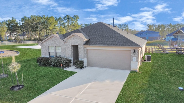 ranch-style home with a garage, fence, a front yard, and roof with shingles