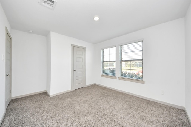 spare room with visible vents, light colored carpet, and baseboards