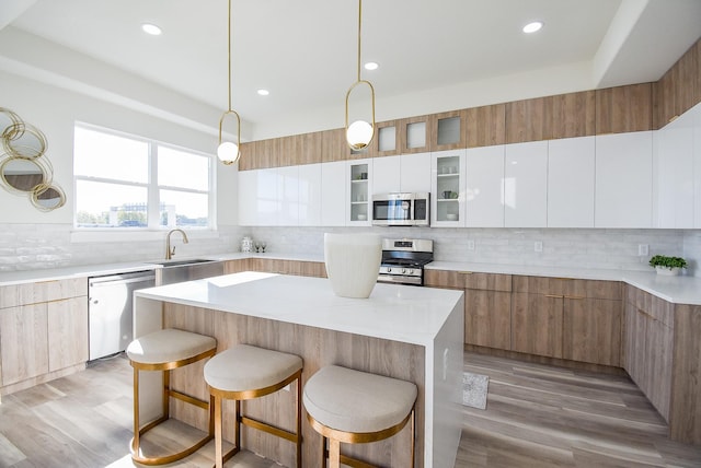 kitchen featuring stainless steel appliances, modern cabinets, a breakfast bar area, and decorative backsplash