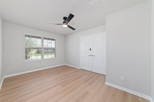 unfurnished bedroom featuring light wood finished floors, baseboards, a closet, and a ceiling fan